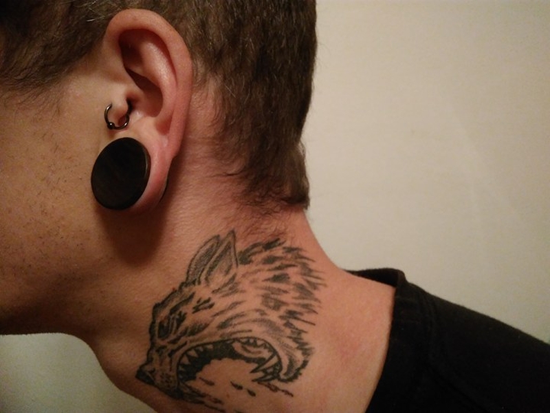 Muž s tetovaním na krku a piercingy v uchu